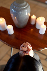 Image showing sad woman with funerary urn praying at church