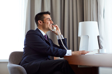 Image showing businessman calling on desk phone at hotel room