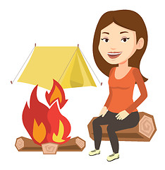 Image showing Woman sitting on log near campfire in the camping.