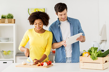 Image showing happy couple with tablet pc cooking food at home