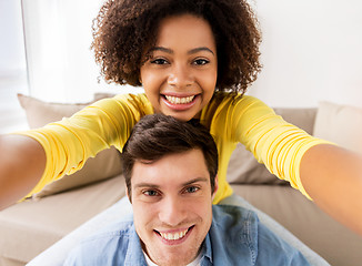 Image showing happy multiethnic couple taking selfie at home