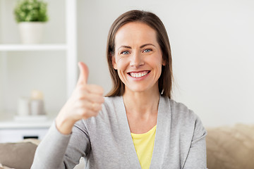 Image showing happy smiling woman showing thumbs up at home