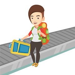 Image showing Woman picking up suitcase on luggage conveyor belt