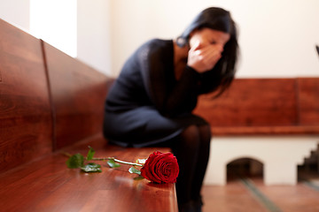 Image showing crying woman with red rose at funeral in church