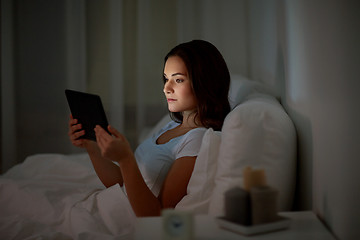 Image showing young woman with tablet pc in bed at home bedroom