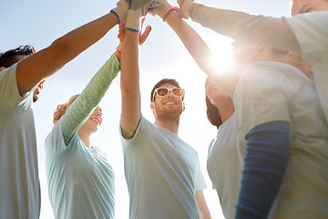 Image showing group of volunteers making high five outdoors