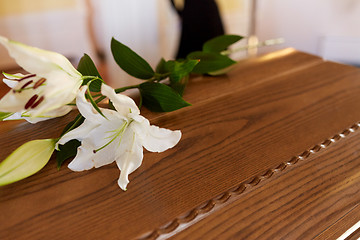 Image showing lily flower on wooden coffin at funeral in church