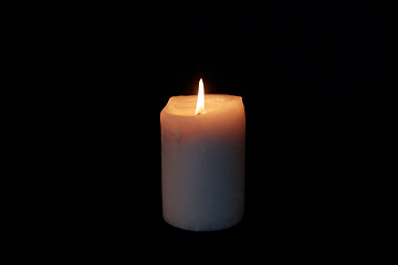 Image showing candle burning in darkness over black background