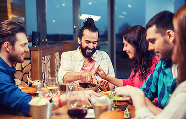 Image showing friends eating and tasting food at restaurant