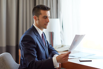 Image showing businessman with papers working at hotel room