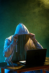 Image showing Hooded computer hacker stealing information with laptop