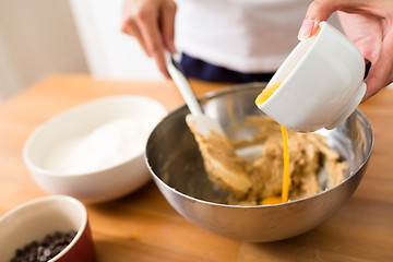 Image showing Adding egg inside the dough for making cookies