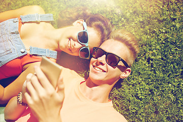 Image showing happy teenage couple smartphone lying on grass