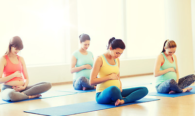 Image showing happy pregnant women exercising yoga in gym