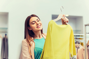 Image showing happy young woman choosing clothes in mall