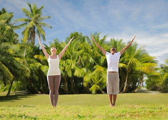 Image showing happy couple making yoga exercises on beach