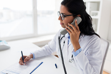 Image showing doctor with clipboard calling on phone at hospital