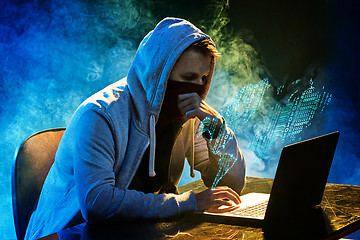 Image showing Hooded computer hacker stealing information with laptop