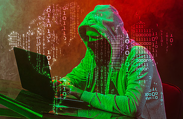 Image showing Hooded computer hacker stealing information with laptop