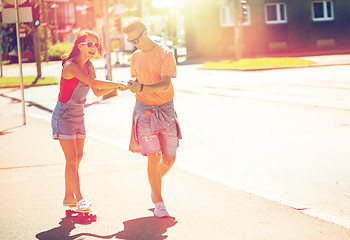 Image showing teenage couple riding skateboards on city street