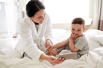 Image showing mother and son with smartphone in bed at hotel