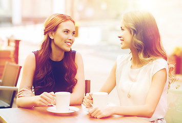 Image showing smiling young women with coffee cups at cafe