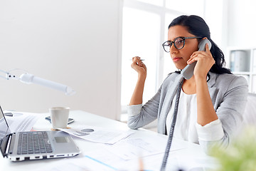 Image showing businesswoman calling on desk phone at office