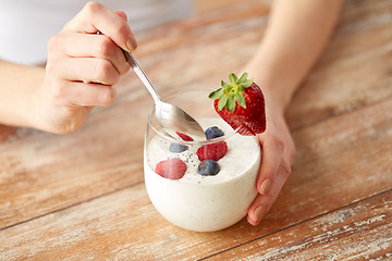 Image showing woman hands with yogurt and berries on table