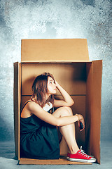 Image showing Introvert concept. Woman sitting inside box and working with phone