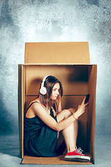 Image showing Introvert concept. Woman sitting inside box and working with phone