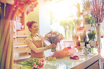 Image showing smiling florist woman making bunch at flower shop