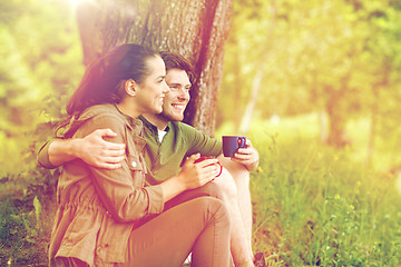 Image showing happy couple with cups drinking tea in nature