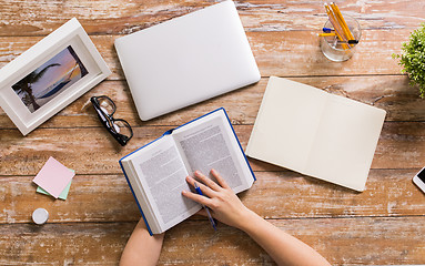 Image showing hands of woman reading book at wooden table