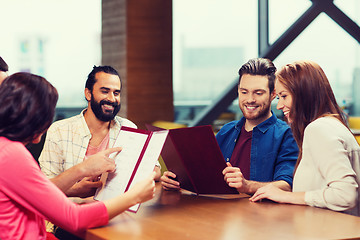 Image showing smiling friends discussing menu at restaurant