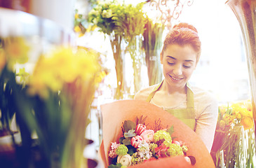 Image showing smiling florist woman with bunch at flower shop