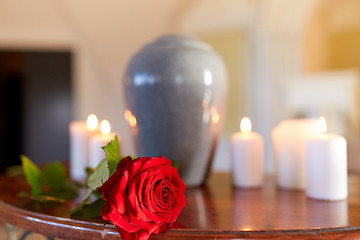 Image showing red rose and cremation urn with burning candles