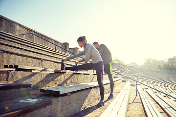 Image showing couple stretching leg on stands of stadium