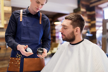 Image showing barber showing hair styling wax to male customer