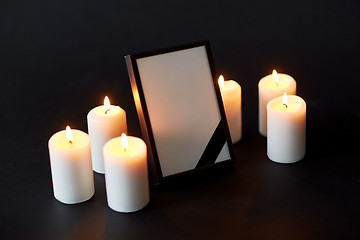 Image showing black ribbon on photo frame and candles at funeral