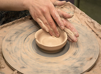 Image showing Woman hands in clay at process of making clay bowl on pottery wh