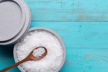 Image showing Sea salt in an stone bowl with small wooden spoon on a blue wooden table