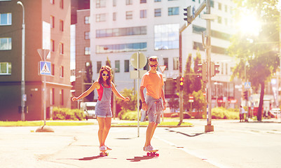 Image showing teenage couple riding skateboards on city street