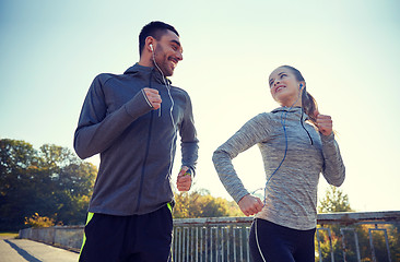 Image showing happy couple with earphones running outdoors