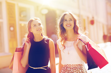 Image showing happy women with shopping bags walking in city 