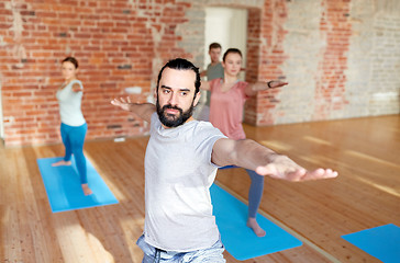 Image showing group of people doing yoga warrior pose at studio