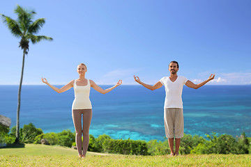 Image showing happy couple making yoga exercises on beach