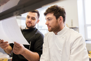 Image showing chef and cook with lists or bills at kitchen