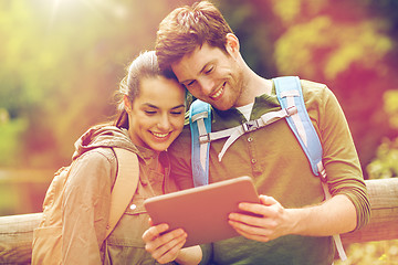 Image showing happy couple with backpacks and tablet pc outdoors