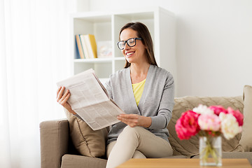 Image showing happy woman reading newspaper at home