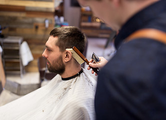 Image showing man and barber with brush cleaning hair at salon